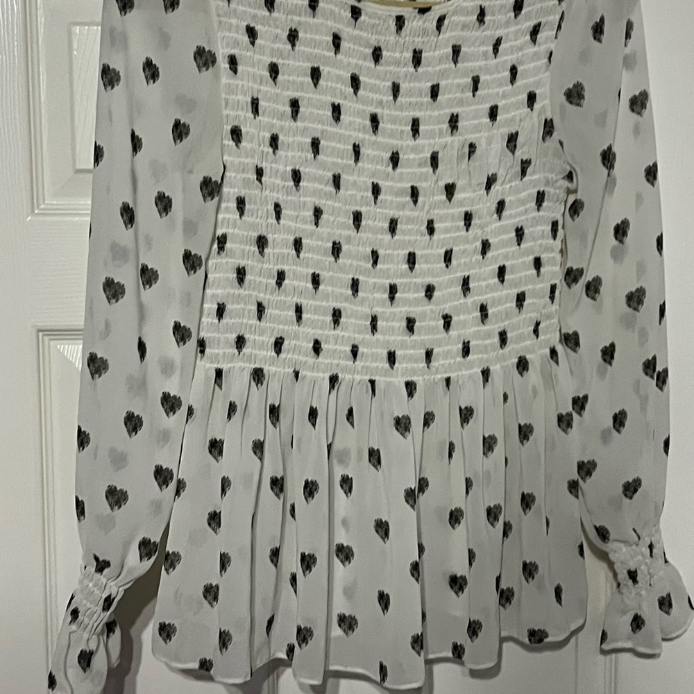 Light and flowing white blouse with cute black hearts. Ruffled at the sleeves.
